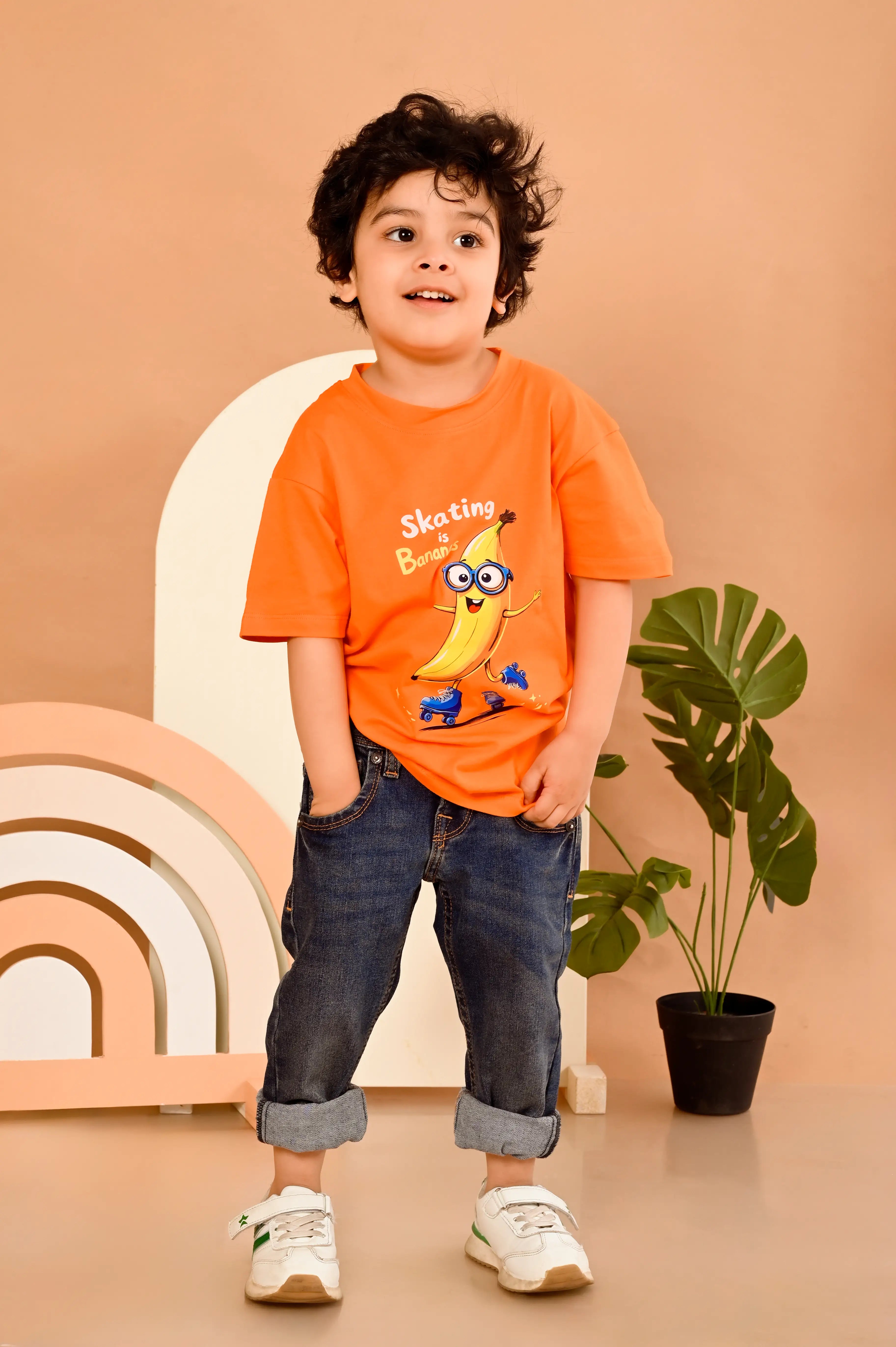 Child wearing an orange t-shirt with a  skating banana with joy graphic